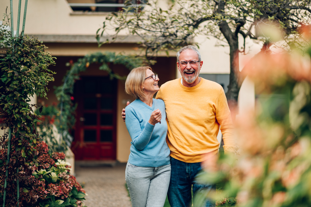 Senior couple holding keys and standing outside their new home senior couple outside their accommodation during their family trip in Springfield Oregon